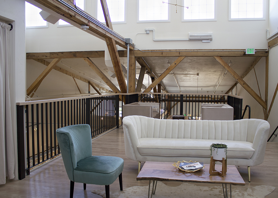 a view of the mezzanine consultation and dressing area featuring concrete floors, exposed wooden beams, and velvet chairs